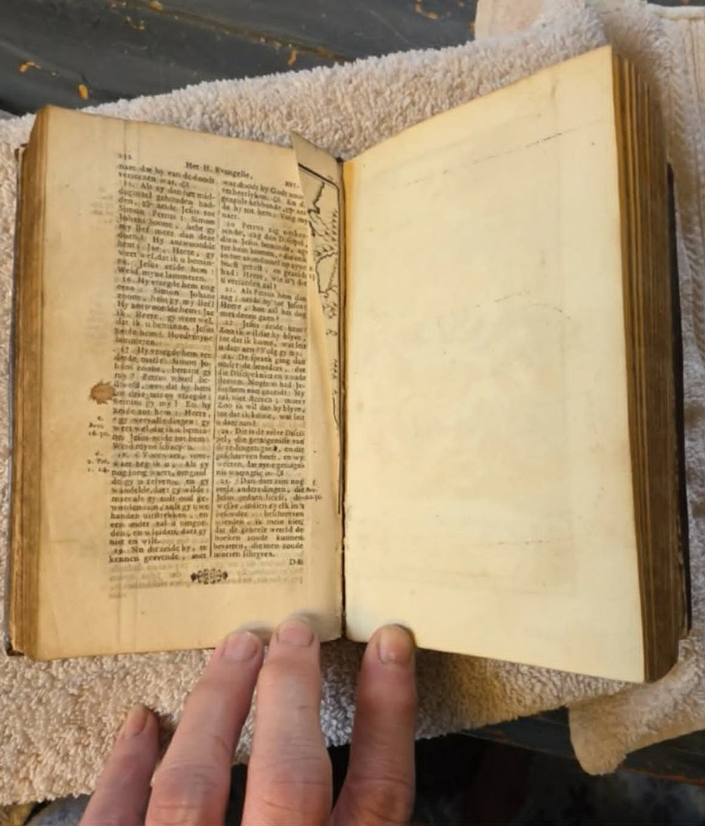 Interior spread showing torn page condition with Dutch text columns, age-appropriate damage, 1720 Dutch New Testament
